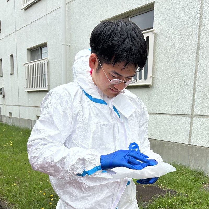 防護服を着て特殊清掃の現場に入る準備をする亀田考明